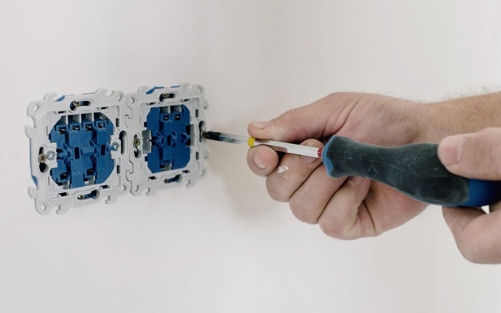 Hands wiring a wall switch mechanism with a screwdriver