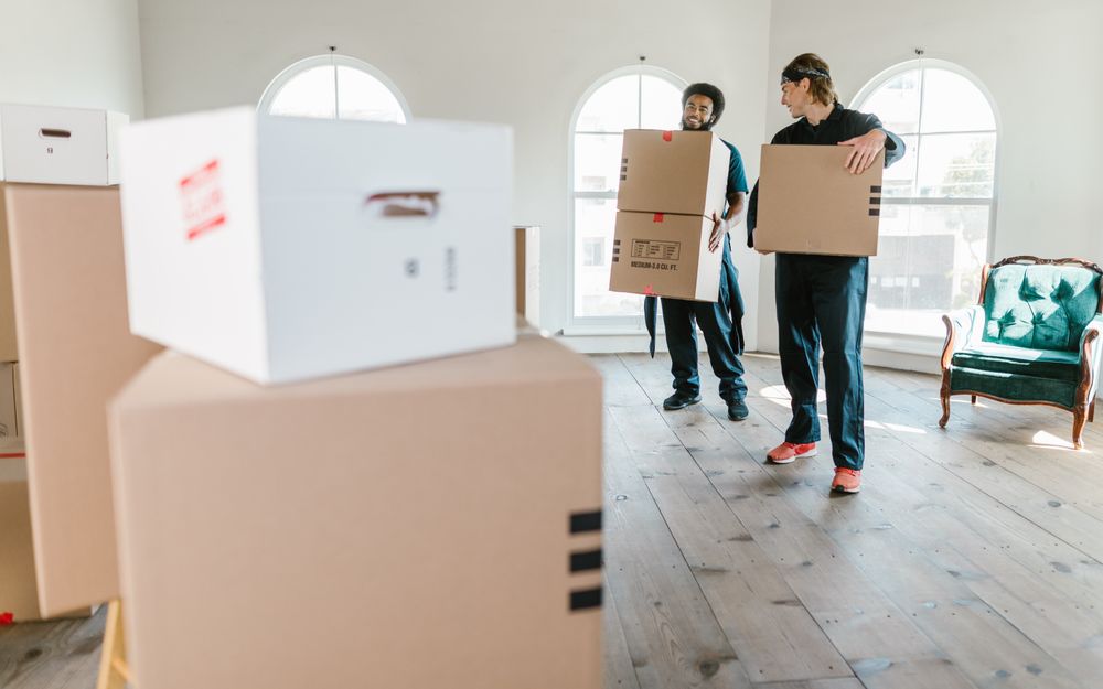 Two Calibre crew carrying cartons into a customer's empty lounge room